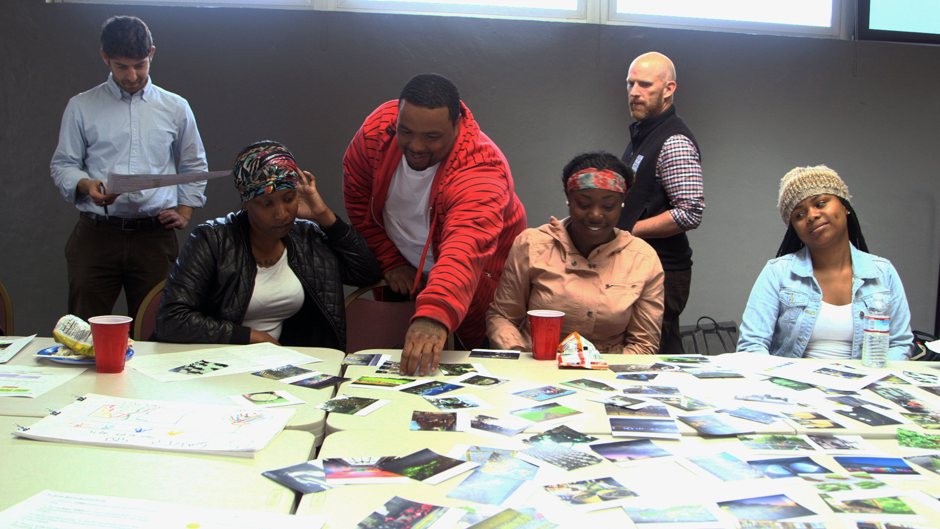 Workshop participants discussing reference photographs spread across a table